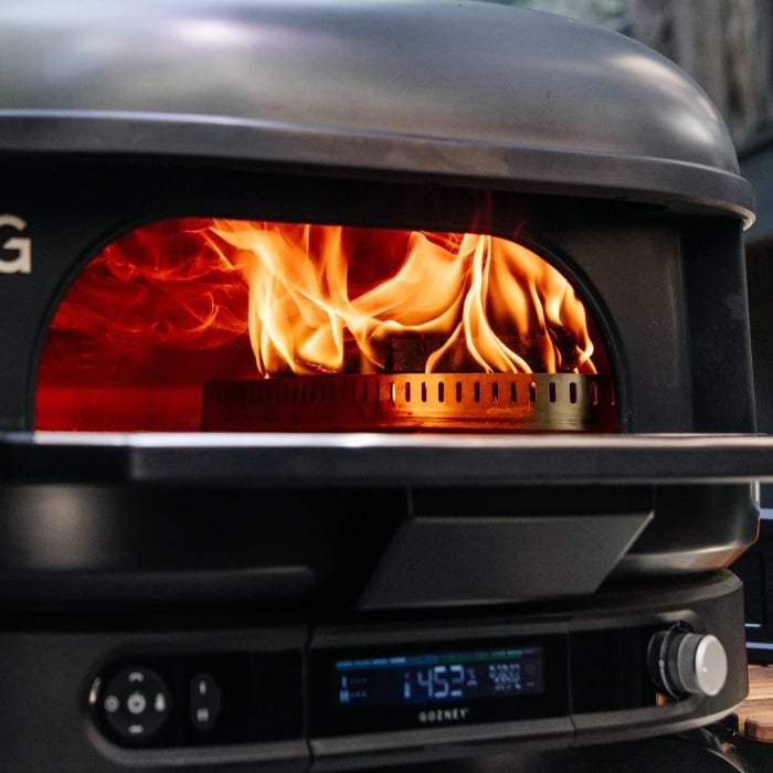 Wood-fired oven with flames inside, showing brand 'Gozney'.