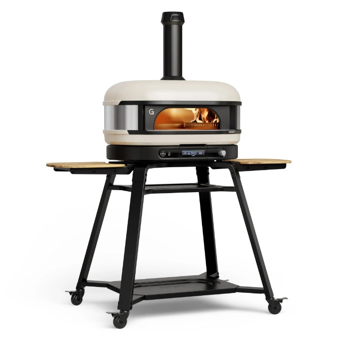 Portable gozney dome xl pizza oven on a stand with visible flames inside, on a white background