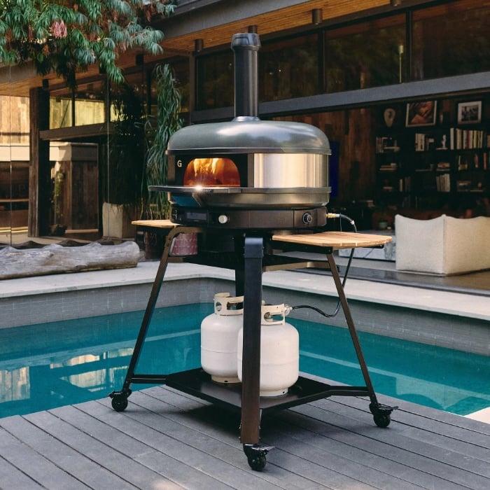 Portable pizza oven on wheels by a poolside outdoor setting