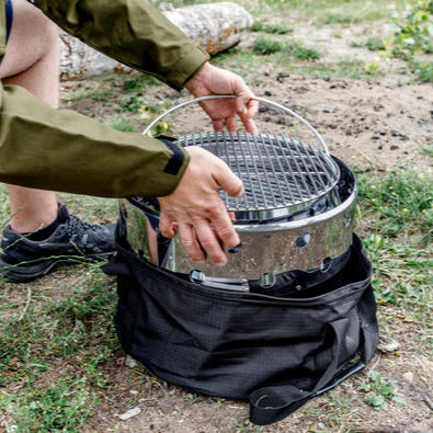 Person setting up a portable grill outdoors