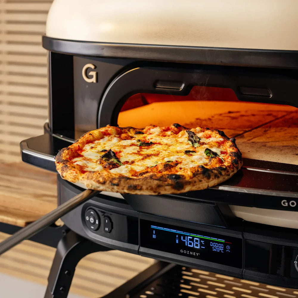 Pizza being taken out of a Gozney Dome Gen 2 pizza oven.